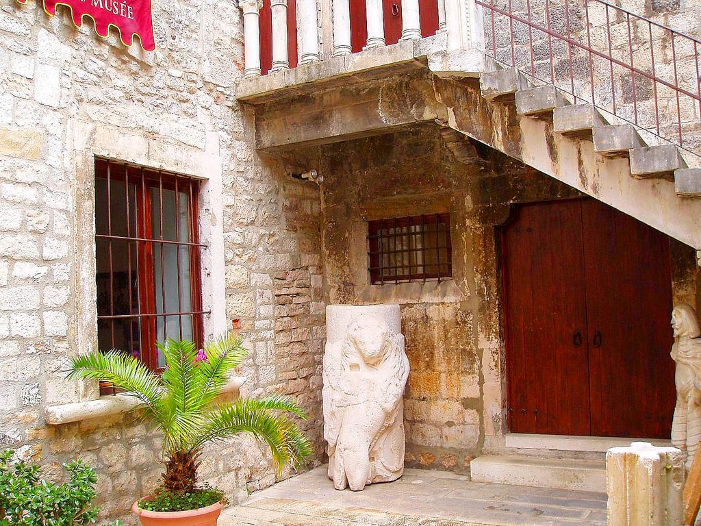 Exterior view of the stone-built Split City Museum with red window frames and doors.