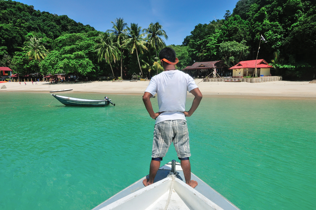 Local surveys the crystal clear water at Kapas island | © Izz Hazel