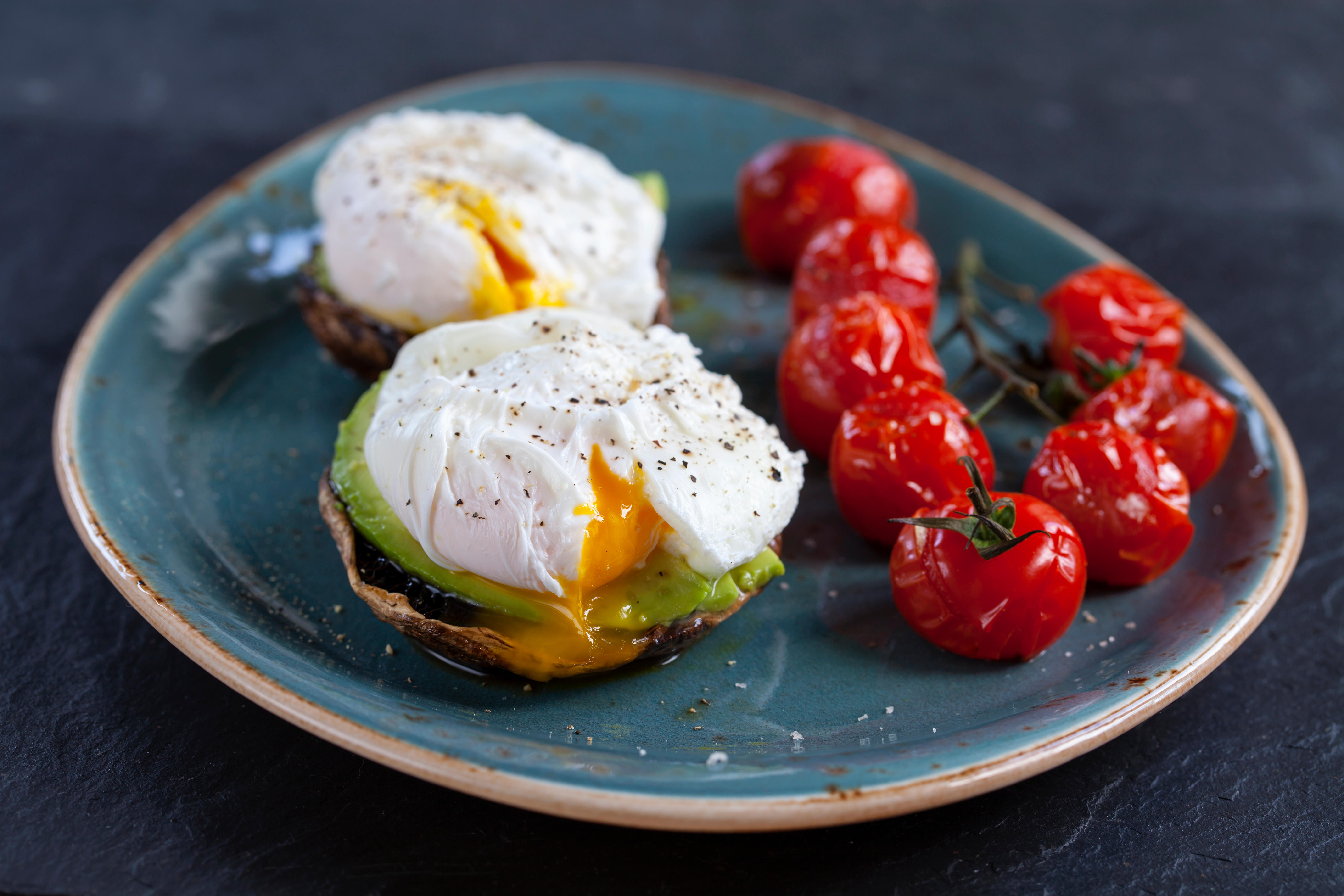 Breakfast, mushrooms with avocado and poached eggs and roast cherry tomatoes on the vine